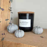 Set of 3 grey concrete pumpkins displayed around a black jar candle. Pumpkin decor