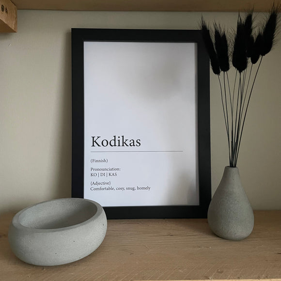 Definition of Kodikas Wall Print. A4 size in black frame. Grey concrete trinket bowl to the left, grey concrete bud vase to the right with black bunny tails