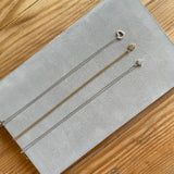 Concrete grey rectangle tray displaying necklaces. 